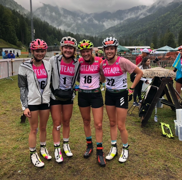 Emily Schumann, Selina Grotian, Charlotte Gallbronner und Iva Moric stehen Arm in Arm vor Alpenkulisse in der Chiemgau-Arena.