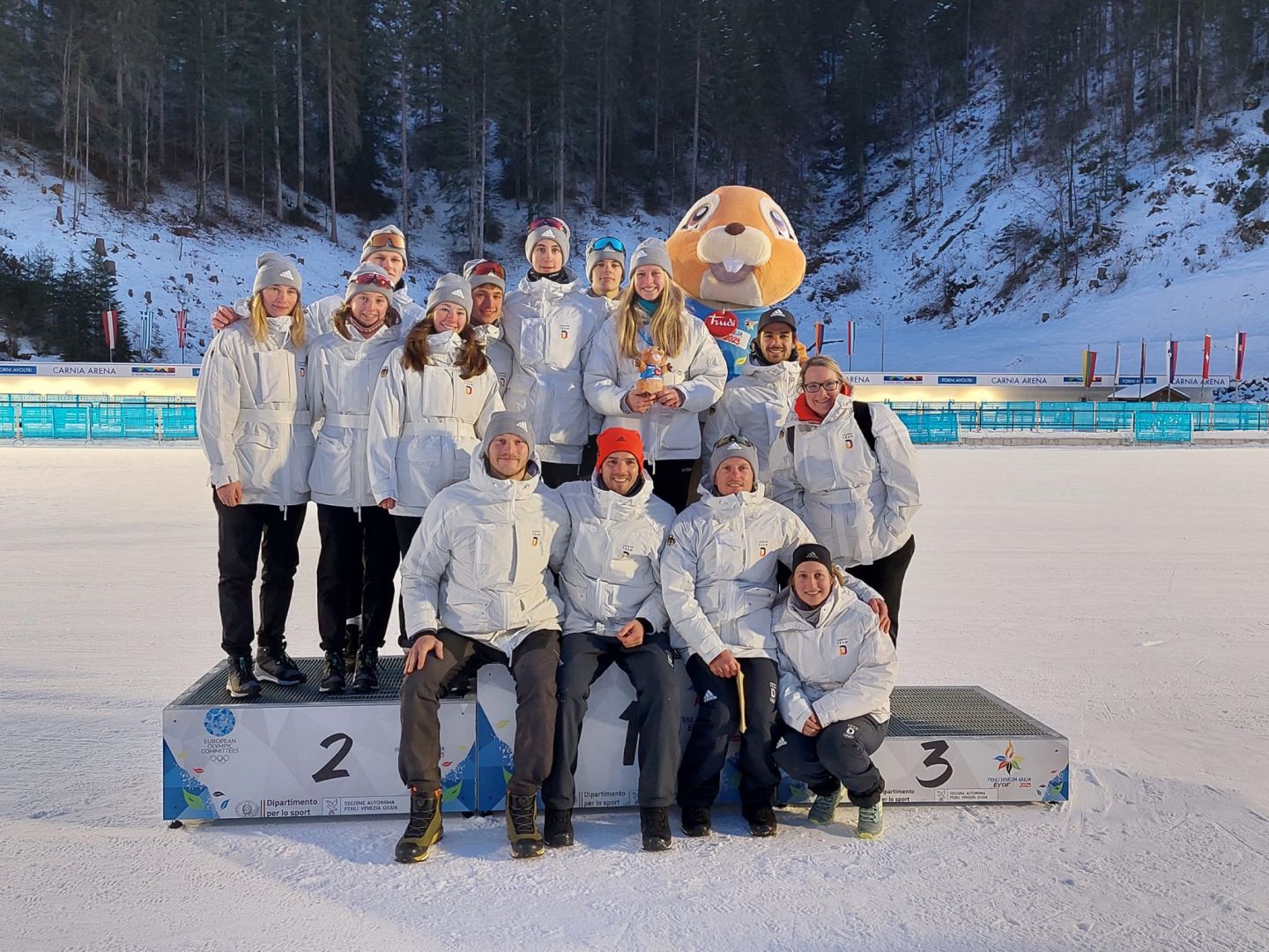 Ein Teamfoto des deutschen Teams auf dem Siegerpodest gemeinsam mit dem Maskottchen des Festivals